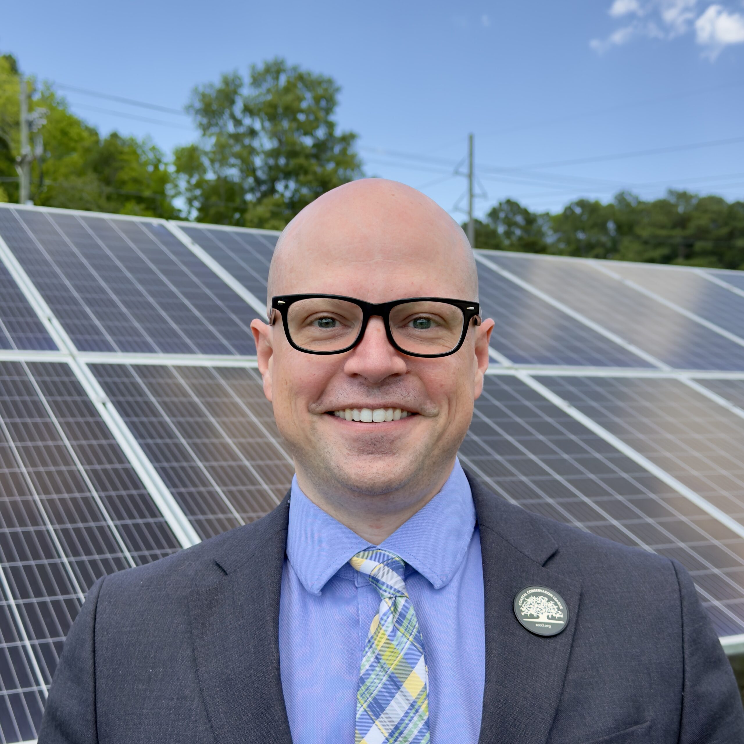 A portrait of a man with solar panels in the background.